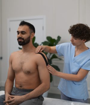 female-therapist-rehabilitation-center-putting-shoulder-support-man